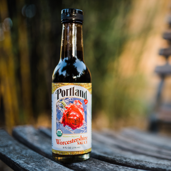 Bottle of Organic Portland Worchestershire sauce sitting in a garden, vegan, gluten free, dairy free, organic condiment