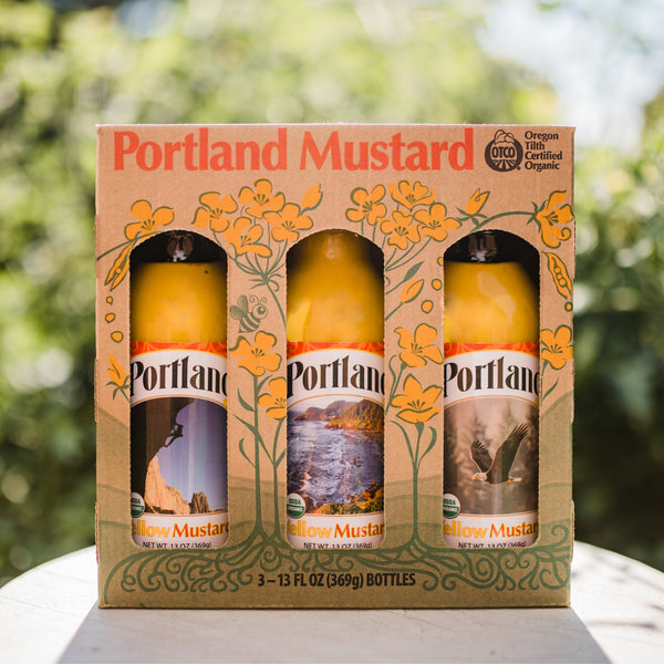 Portland Organic Mustard 3-Bottle Gift Pack sitting on a table outside, no GMOs, Gluten Free, Dairy Free 