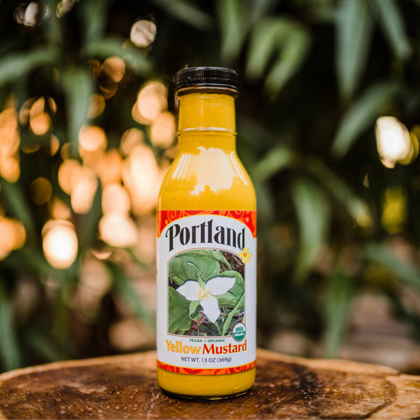 Bottle of Portland Organic Yellow Mustard sitting outside in the sunshine, non dairy, gluten free, non GMO, vegan condiment
